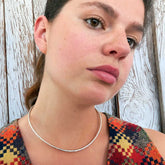 Close-up of a person wearing a silver necklace against a wooden background